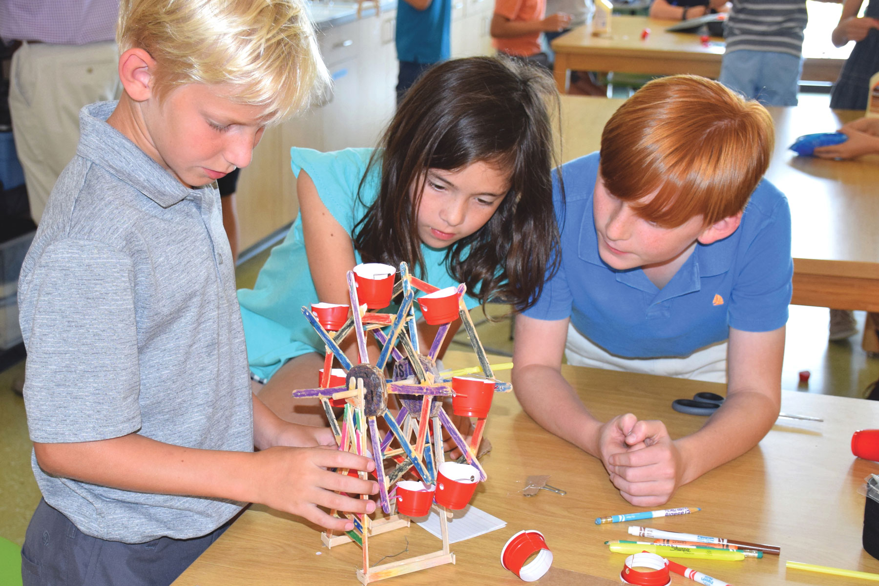 Children creating a ferris wheel out of art class materials